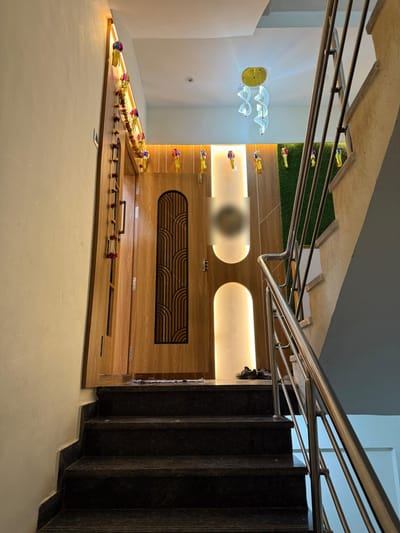 Entrance foyer with wood-finish main door, backlit arch panels and pendant light
