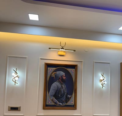 Living room feature wall with white moulding panels, gold wall lights and cove-lit false ceiling