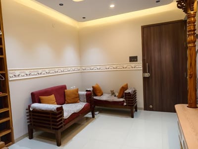Sitting area with cove-lit false ceiling, elephant-motif wall border and wooden sofas